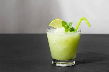 Kokteyl suyu limon, nane ve buz ile. Siyah tablo arka plan üzerinde bar içki aksesuarları.