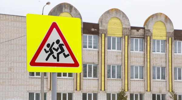 Road sign, caution children, on the background of the building.