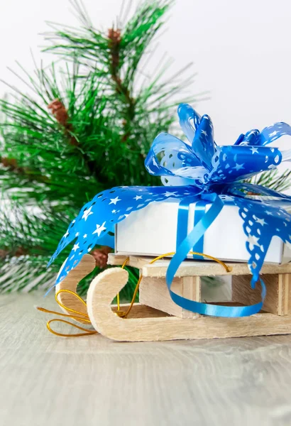 大きな青い弓を持つクリスマスの贈り物は木製のそりに横たわっています 新年と陽気なクリスマス — ストック写真