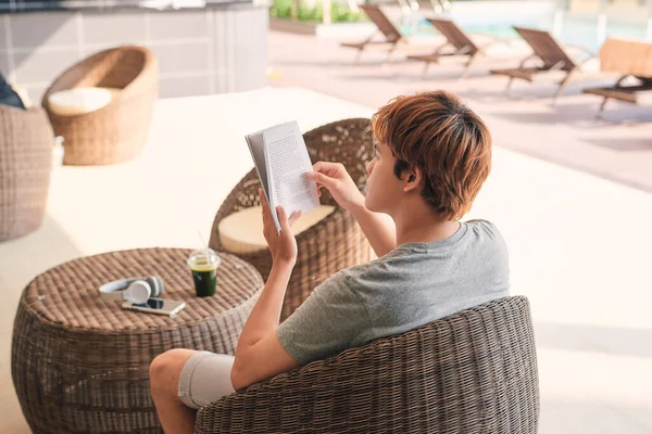 Young Man Lying Chaise Lounge Reading Book Swimming Pool — Stockfoto