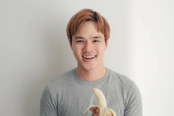 Ung Man Äter Banan Över Grå — Stockfoto