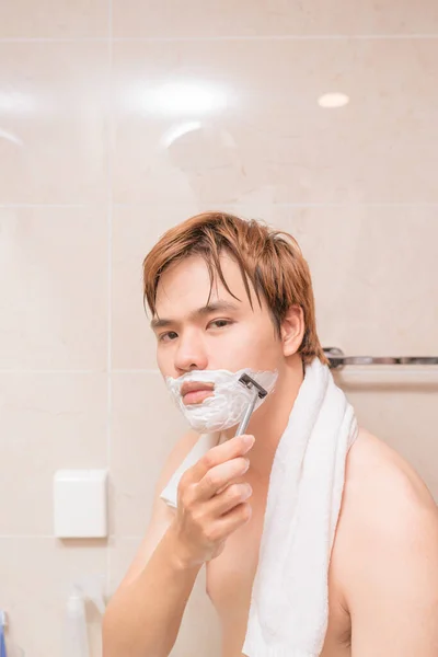 バスルームでひげを剃ってハンサムな若い男 — ストック写真
