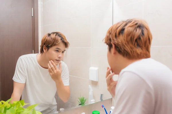鏡で見ていると バスルームで彼の皮膚をチェック — ストック写真