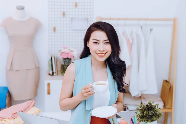 美丽的年轻亚洲时装设计师女商人在她的工作室 而喝咖啡的肖像 — 图库照片