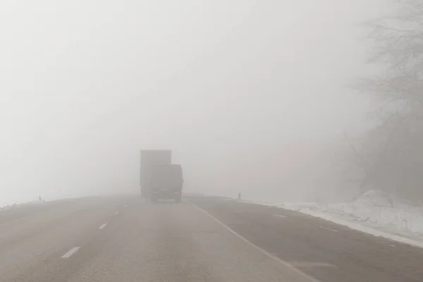 霧の多い道を走るトラックは — ストック写真