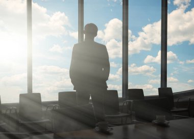 Ofisin penceresinin yanında duran erkek işadamı.