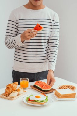 Adam kahvaltıda taze karpuz ve ekmek yiyor.