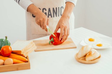 Male hands slicing red bell pepper on wooden cutting board