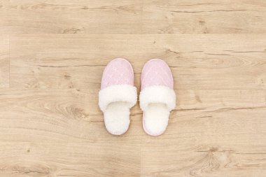 Pembe örülü terlikler halının üzerinde 