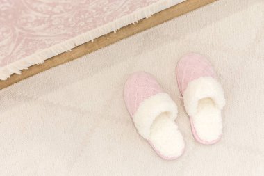 Pembe örülü terlikler halının üzerinde 