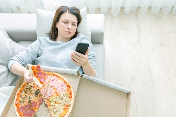 Mujer Triste Comiendo Pizza Sosteniendo Teléfono Acostado Sofá Casa Tono — Foto de Stock