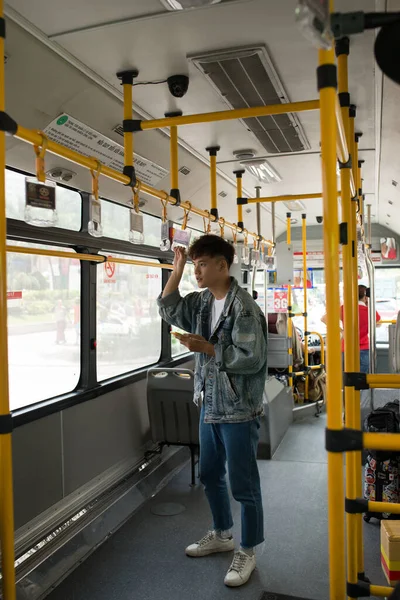 バスの中の人 公共交通機関でスマートフォンを使うアジア人 — ストック写真