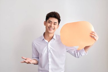 Klasik gömlek yakışıklı asya adam bir konuşma balonu tutuyor ve gülümseyerek, beyaz duvarda ayakta