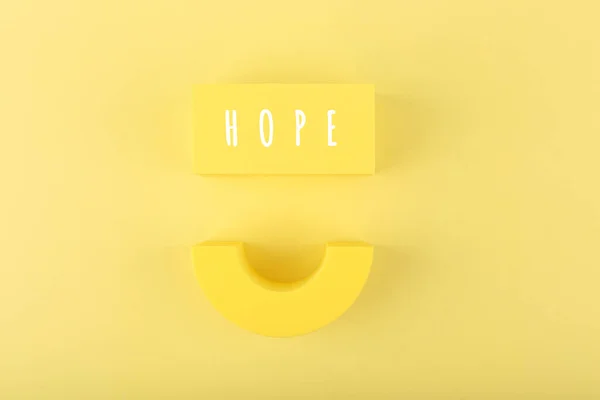 在明亮的黄色背景下带着微笑的精神乐观的最小希望的概念 — 图库照片