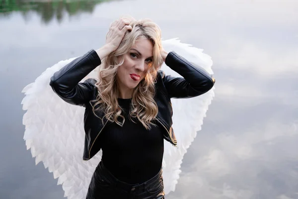白い天使の翼を持つ女性 黒い革の服を着て 堕落したダークエンジェル ハロウィンの天使の衣装を着た女の子 — ストック写真