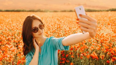 Haşhaş çiçeğinin otlağında selfie yapan kız.