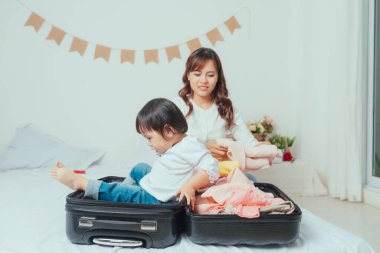 Mom and daughter are packing suitcases for the trip.