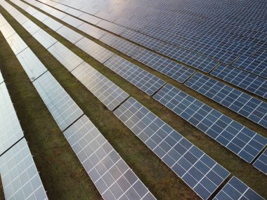 Bir güneş paneli enerji santralinin havadan görünüşü. Güneşin doğuşunda ve batışında yukarıdan fotovoltaik güneş panelleri. Modern teknoloji, iklim bakımı, toprak tasarrufu, yenilenebilir enerji kavramı. 