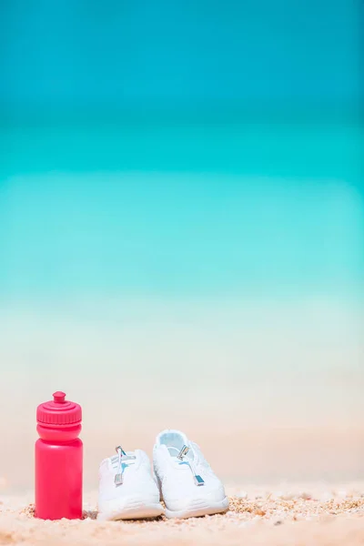 运动鞋和白色沙滩上的瓶子 — 图库照片