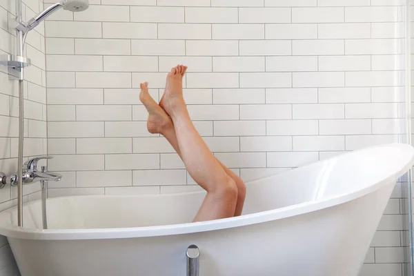 一个无名的赤脚女子躺在白色浴缸里冷着 — 图库照片
