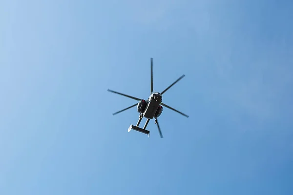 Small civil helicopter flies against a blue sky with clouds background