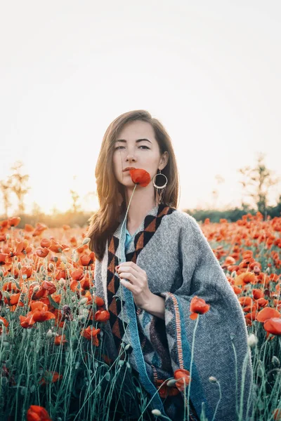 一个迷人的女人站在户外的田里 手里拿着一个罂粟 — 图库照片