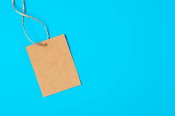 Craft brown paper tag isolated on blue background. Sale banner with copy space in minimal style