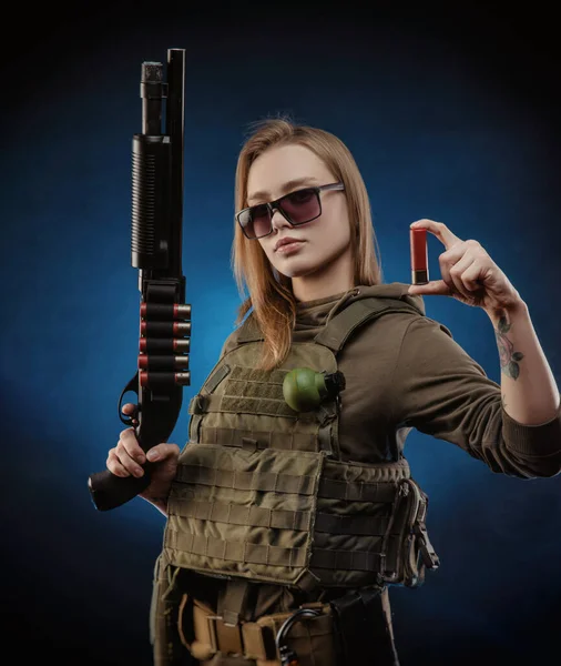身着军服的女孩摆出一副软弱无力的姿势 手里拿着枪 背景阴沉沉的 — 图库照片