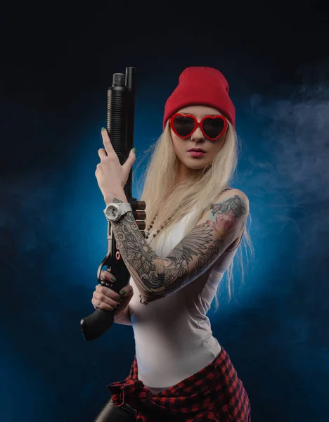 Kırmızı Şapkalı Siyah Arka Planda Pompalı Tüfekli Parlak Bir Sarışın — Stok fotoğraf