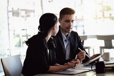 Konsültasyonda, erkek bir danışman kadın işadamlarına kar yapılandırmasını açıklamak için bir tableti işaret etmek için bir kalem kullanır.