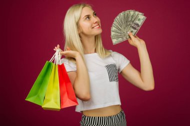 Mutlu kız yüz dolar faturaları ve alışveriş çantaları tutar
