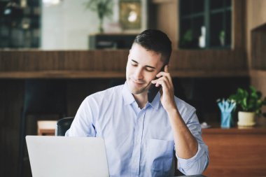 Erkek pazarlama müdürü, kâr potansiyelini artırmak için risk sermayesi şirketiyle konuşmak için telefonu kullanıyor..