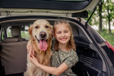 Arabasında golden retriever köpeği olan genç bir kız.