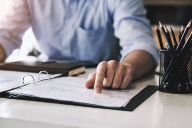 Examining the financial budget, a male auditor is pointing to a file to summarize the company's irregular financial budget.