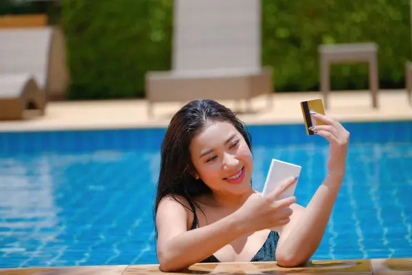 online payment, A teenage girl who swims is using her credit card with her phone to make purchases. online via internet