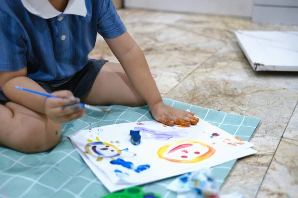 Focus on hands on paper, early childhood learning by using paints and brushes to build imagination and enhance skills on the board