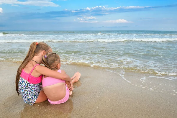 2人の女の子がビーチに座って海を見ている 海のビーチや美しいスカイラインの子供たち — ストック写真
