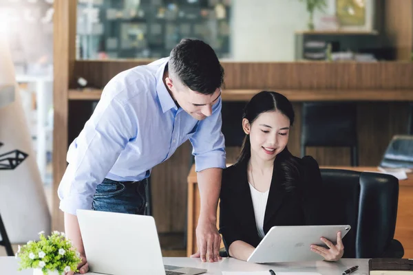 stock image The male marketing manager expressed his satisfaction in selling the company's products. where team members show sales from their iPad screen.