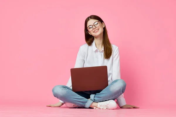女人坐在地板上 带着笔记本电脑购物娱乐粉色背景 — 图库照片