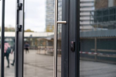 Ofis bloğunun ön kapısı, camdaki binaları yansıtıyor.