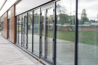 Ofis bloğunun ön kapısı, camdaki binaları yansıtıyor.