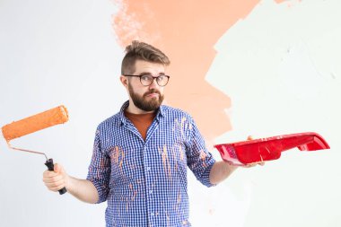 Yeni dairesinde duvar boyayan bir adam. Yenileme ve dekorasyon konsepti.