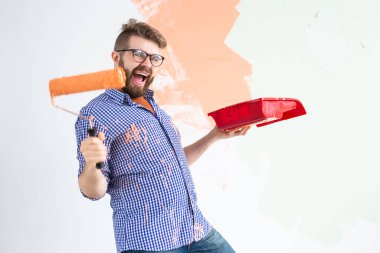 Kapalı mekanda resim yapan komik bir adam. Dekorasyon, yenileme, apartman onarımı ve ferahlatıcı konsept.
