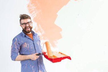 Yeni evde duvarları boya rulosuyla boyayan mutlu adam. Duvara boya süren patenli bir adam..
