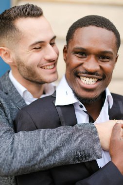 İki kucaklaşan ve gülümseyen adamın portresi, Kafkasyalı ve Afro-Amerikan.