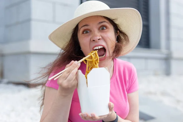 暖かい夏の日の散歩中に公園で中華麺とポーズをとる帽子をかぶった若い狂気の少女のクローズアップ おいしい食べ物のコンセプト — ストック写真