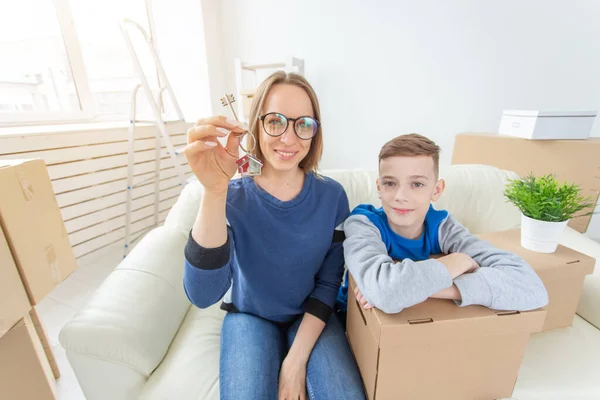 Hämärtynyt Positiivinen Äiti Poika Istuvat Sohvalla Osoittavat Avaimet Uuteen Asuntoon — kuvapankkivalokuva