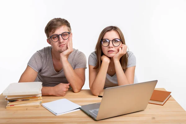 stock image Education and people concept - couple of young people in glasses look like they are bored of learning homework