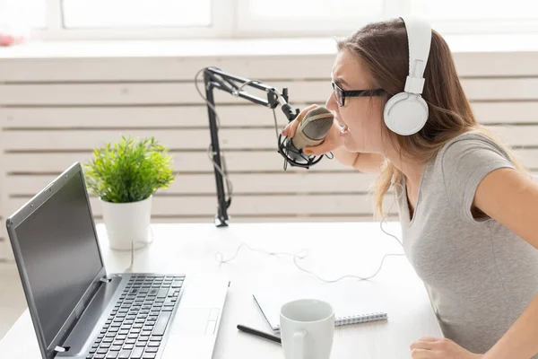 ラジオホストコンセプト スタジオの白い背景の上にマイクの前に座ってラジオホストとして働く女性 — ストック写真