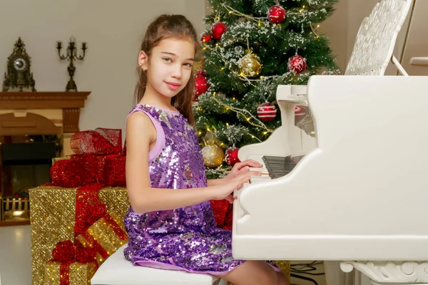 ピアノとクリスマス ツリーの近くの小さな女の子 — ストック写真